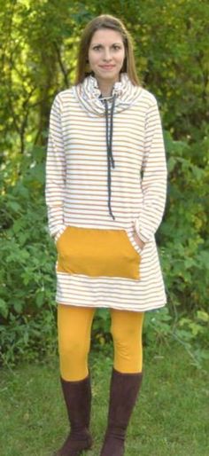 a woman standing in the grass with her hands on her hips wearing yellow tights and brown boots