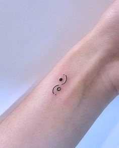 a small black and white tattoo on the wrist