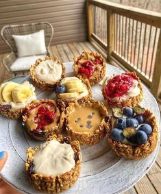 a white plate topped with mini pies covered in toppings and fruit on top of it