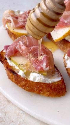 a person is spreading cheese on top of bread with a honey stick in the middle