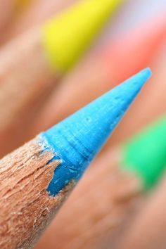 a close up shot of a pencil with colored crayons in the background