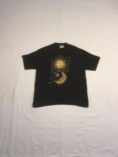 "vintage 1990s t-shirt total cotton, shrinkage controlled Lee made in USA black w/gold/blue/purple,yellow sun/moon print good vintage condition, light wear/discoloration below print(see photos) labeled size L, see below measures, lying flat, shoulder-20\" sleeve-8\" chest-21 1/2\" length-28 1/2\"     We do not offer returns or refunds unless something is grossly misrepresented. Please contact us within 2 business days of receiving to discuss any possible returns for this reason. We do not offer refunds for your shipping fees. Please feel free to contact us with any questions you may have about an item prior to purchase and we will gladly answer them." Bohemian Short Sleeve T-shirt For Streetwear, Vintage Gold Top With Graphic Print, Vintage Gold Tops With Graphic Print, Gold Vintage Tops With Graphic Print, Vintage Gold Crew Neck Top, Bohemian Short Sleeve T-shirt With Sun And Moon Design, Bohemian Cotton T-shirt With Sun And Moon Design, Graphic Tee With Moon Print For Festival, Celestial Cotton T-shirt With Crew Neck