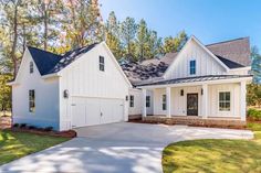 a white house with two garages on the front and one story, surrounded by trees