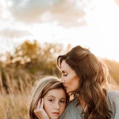 a mother and daughter hugging each other in a field