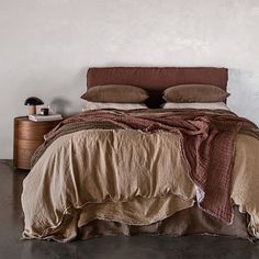 a bed with two pillows on top of it next to a night stand and nightstand