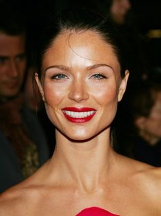 a woman in a red dress smiling at the camera