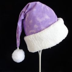 "This festive Santa hat is made up in a soft and cozy violet purple tie dye pattern cotton flannel fabric. The flannel is accented with a white Faux Sherpa fur turn up brim. Proportions of the hat are generous and will fit most head sizes, ladies or gents.   Measurement for opening for your head is 24-25\" circumference and the length is 19\".  There is a snowy white faux fur dangle pompom on the tip. If you need more than the number of hats offered in this listing, just send me a message.  Cust Purple Hat As A Gift, Purple Hats As Gifts, Purple Cap As A Gift, Purple Winter Hat With Curved Brim, Purple Santa, Christmas Santa Hat, Santa Helper, Purple Christmas, Tie Dye Pattern