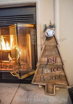 a wooden christmas tree sitting next to a fireplace