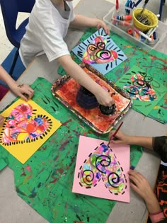 children are painting on paper at a table