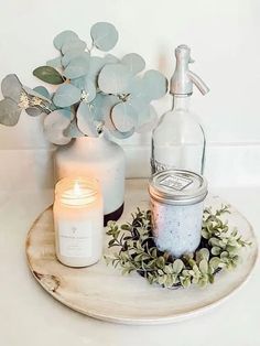 there is a candle and some bottles on the table next to each other with flowers in them