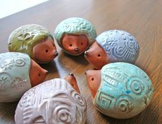 five ceramic hedges sitting on top of a wooden table next to each other in different colors