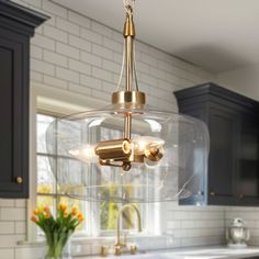 a kitchen with an island, sink and large glass bowl chandelier hanging from the ceiling