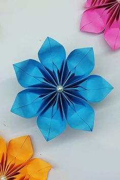 three origami flowers sitting next to each other on top of a white table