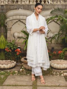 This graceful kurta suit set is crafted from white cotton dobby fabric, known for its subtle textured weave that adds a unique dimension to the outfit. The straight-cut kurta showcases clean lines and a timeless silhouette, making it ideal for both casual and semi-formal wear. The kurta is further enhanced with delicate cotton lace trims, providing a touch of elegance and intricate detail that complements the natural texture of the dobby fabric. The ensemble includes matching bottoms, completing the look with a cohesive and comfortable fit. Accompanying the kurta is a sheer organza dupatta, adding a hint of luxury with its lightweight, flowing quality. The dupatta is often lightly embellished or bordered with lace to harmonize with the understated charm of the kurta, creating a balanced ye Straight Suit, Semi Formal Wear, Dobby Fabric, Organza Dupatta, Lace Trims, Organza Fabric, Suit Set, Cotton Lace, Natural Texture