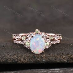 an opal and diamond ring sits on top of a piece of stone in front of a dark background