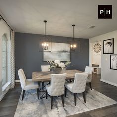 a dining room table with white chairs in front of a gray wall and clock on the wall