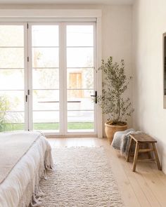 a bedroom with white walls and wooden flooring next to a large sliding glass door