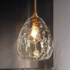 a clear glass light hanging from a ceiling fixture in a room with a mirror behind it