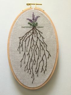 a cross stitch pattern with flowers and roots on the hoop hanging from a wall hanger