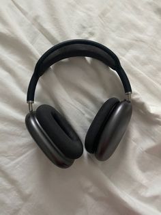 two black headphones laying on top of a white sheet