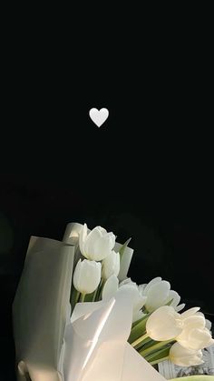 white tulips and other flowers with a heart shaped object in the background