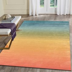 a living room with an orange, yellow and blue area rug on the hardwood floor