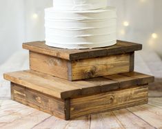 three tiered wooden cake stand with white frosting stacked on top of each other