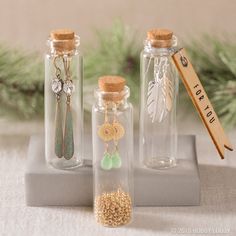 three glass bottles filled with different types of earrings