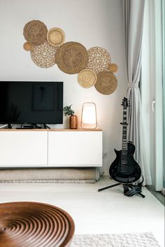 a living room with a guitar on the floor next to a wall mounted flat screen tv