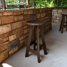 two wooden stools sitting in front of a stone wall