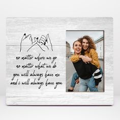 a white wooden frame with an image of two people holding each other and the words no matter where we go, no matter what we do