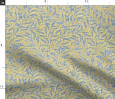 a yellow and blue fabric with small leaves on the side, in front of a ruler