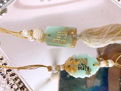 two necklaces with pearls and beads hanging on a glass table next to a mirror