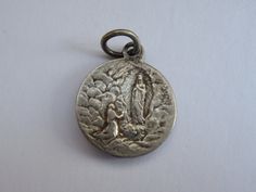 Religious antique French silver ( MARKED ) catholic medal pendant charm medallion of Holy Virgin Mary of Lourdes. Measures are 0,659 x 0,7 inches ( 1,52 x 1,79 cm ) I bought this beautiful antique medal on a brocante ( fleamarket ) in France. I deliver all over the world. If you want more photos or information, you can contact me. If you don't have paypal, you can pay by bank transfer. Registered shipping is possible. Please take a look at my other items for sale.Registered shipping is possible Miraculous Medal For Commemoration, Miraculous Medal Medallion For Commemoration, Vintage Miraculous Medal On Round Pendant, Vintage Miraculous Medal Medallion Jewelry, Vintage Miraculous Medal Medallion, Vintage Miraculous Medal Round Pendant, Silver Miraculous Medal Pendant, Silver Pendant With Miraculous Medal, Our Lady Of Sorrows