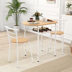 a table with two chairs next to a potted plant and some food on it