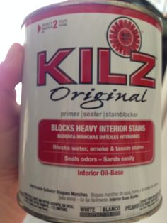 a hand holding a can of killz sealer in it's left hand