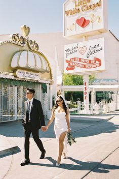 a man and woman holding hands walking down the street