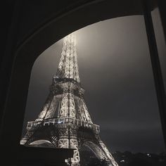 the eiffel tower lit up at night in black and white, as seen from below