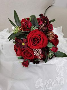 a bridal bouquet with red roses and greenery