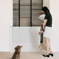 a woman holding a baby in her arms while standing next to a dog looking at it