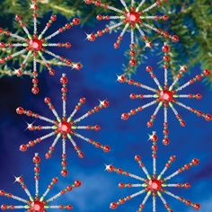 three red and white snowflakes hanging from a christmas tree with blue sky in the background