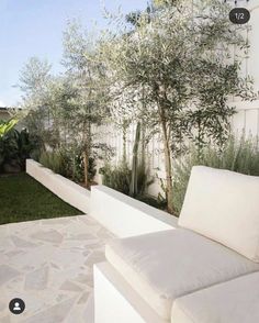 a white couch sitting in the middle of a lush green yard