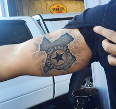 a man's arm with a star and clock tattoo on it, in front of a white truck