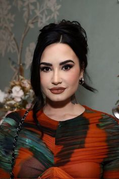 a close up of a person wearing an orange and black dress with flowers in the background