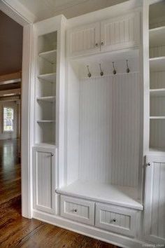 an empty room with white cabinets and drawers on the wall, in front of a wooden floor