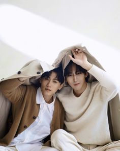 two young men sitting next to each other under a blanket