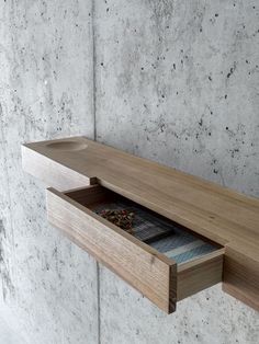 an open drawer on the side of a concrete wall next to a wooden shelf with various items in it