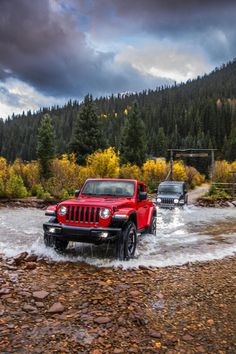 two red jeeps driving through a river