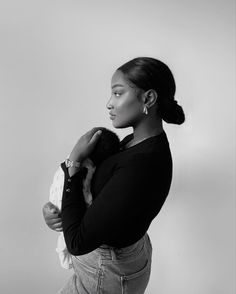 a black and white photo of a woman holding a baby in her arms, looking off to the side