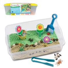 a plastic container filled with dirt and toys next to a box of sand, scissors and flowers